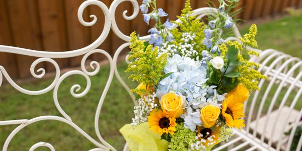 Colorful bouquet on a white metal garden bench.