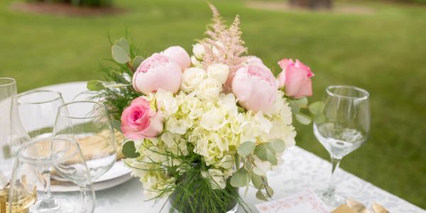 Elegant floral centerpiece with pink and white flowers on a table outdoors.