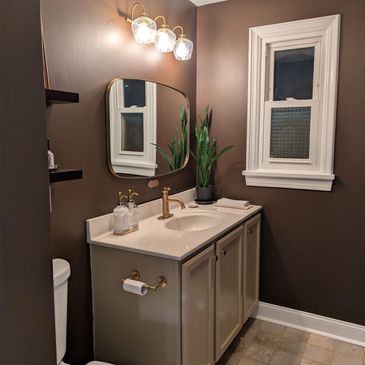 Elegant bathroom with brown walls, white vanity, and gold fixtures.
