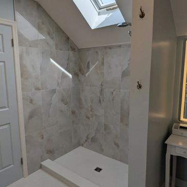 Modern shower area with marble tiles and skylight above.