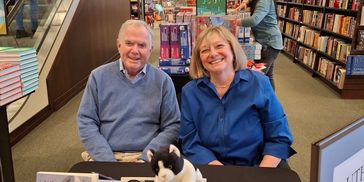 Two people smiling at a book signing event in a bookstore.
