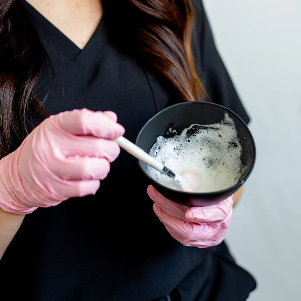 Person wearing pink gloves mixing foam in a black bowl.