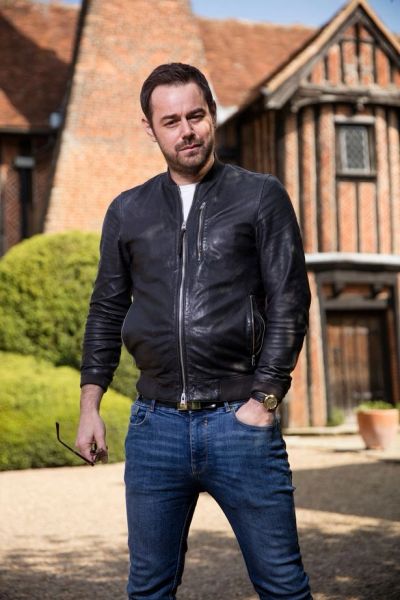 Man in leather jacket and jeans outdoors.