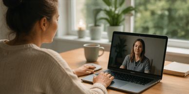 Woman video chatting on laptop at a cozy wooden desk.