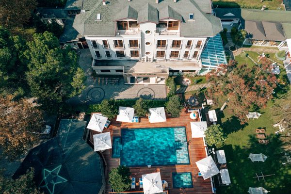 Butik otel bina çekimi ve havadan açık havuz görüntüsü. Bahçede hamaklar ve koltuk takımları.