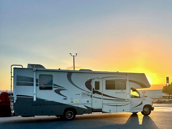 The Green Machine RV parked at sunset, casting a warm glow on the open road.