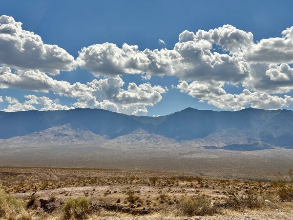 A stunning desert landscape with towering mountains, a clear blue sky evoking adventure and serinity