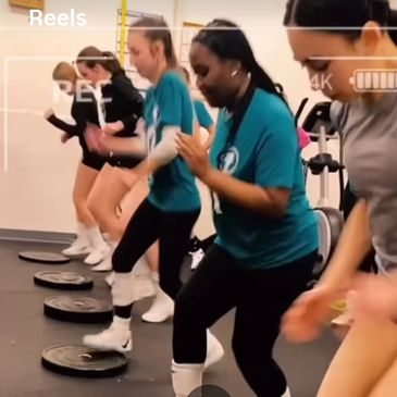Group of women exercising together in a gym setting.