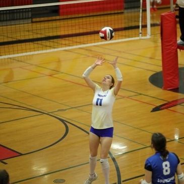 Female volleyball player setting the ball during a game.