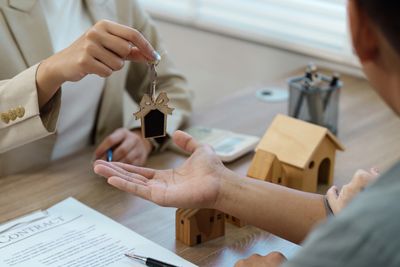 Real estate agent handing over house keys to a client after signing a contract.