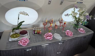 Elegant table setup with flowers and drinks inside a plane.