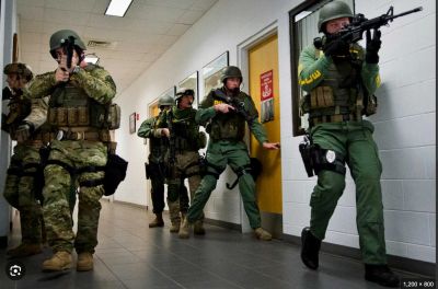 Tactical team in military gear advancing in hallway.