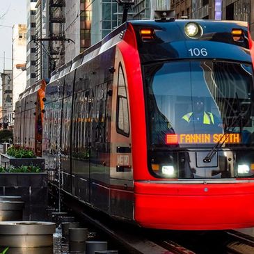 Modern red and black city tram at Fannin South stop.
