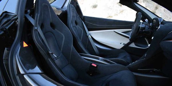 Interior of a sleek sports car with black bucket seats and carbon fiber accents.