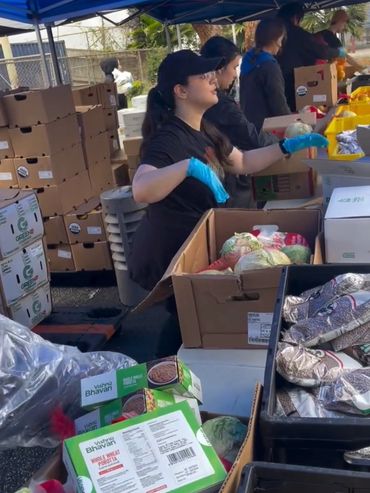 Volunteers packing food supplies under a blue tent.