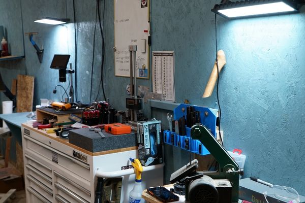 A well-organized workshop with tools and equipment on a blue wall and white drawers.