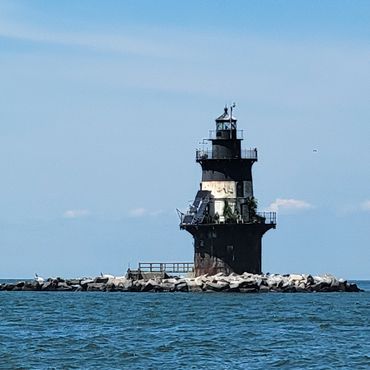 Black lighthouse on a rocky coastline.