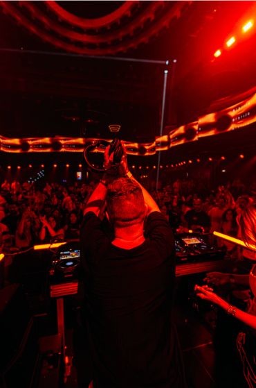 DJ tocando en un club con luces rojas.