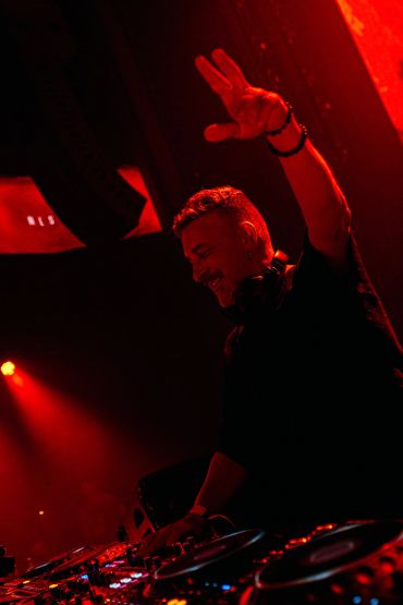 DJ en una fiesta con luces rojas.
