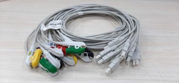 Coiled multi-colored electrode cables on a light wood surface.