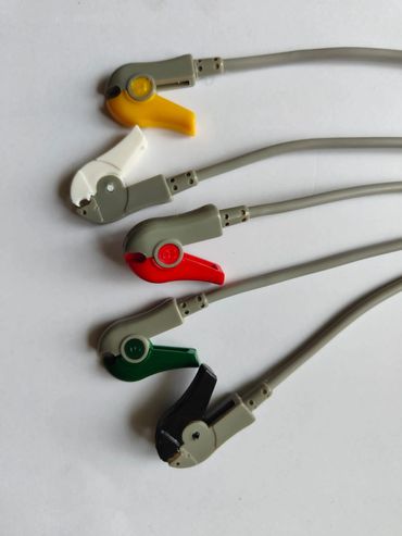Five differently colored ECG electrode clips arranged neatly on a white surface.