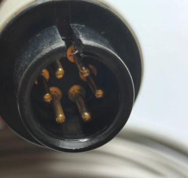 Close-up of a black circular electrical connector with five gold pins.