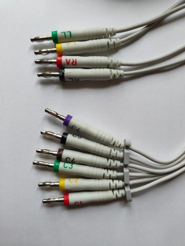 Set of color-coded medical electrode cables on a white surface.
