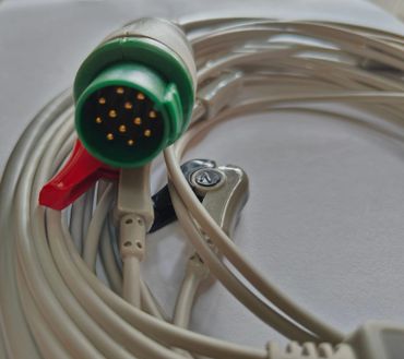 Close-up of a coiled multi-pin connector cable with clips on a white surface.