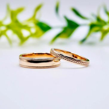 Two elegant rose gold rings with beaded edges on a white surface.