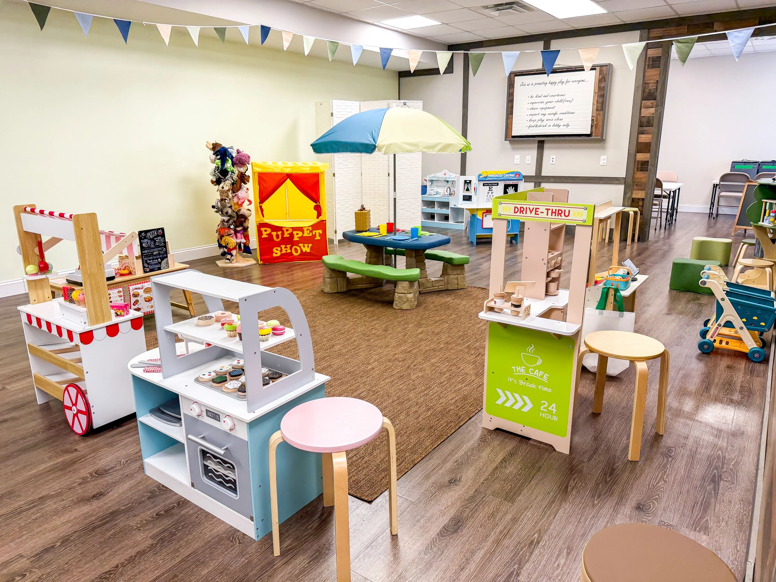 Colorful indoor children's playroom with various toys and activity stations.