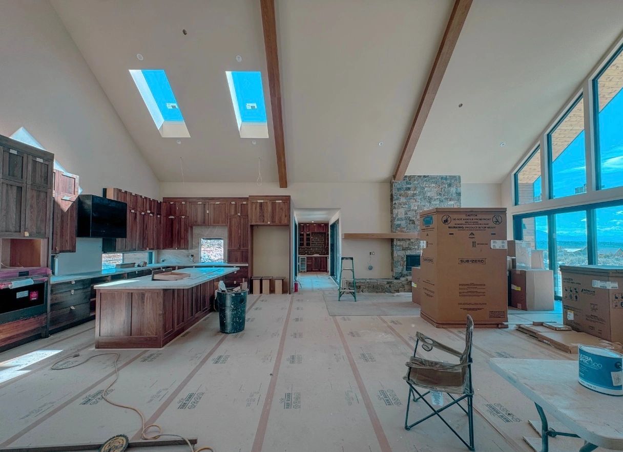 Spacious kitchen under construction with large windows and high ceilings.