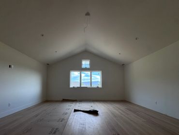 Empty room with wooden floor and a window showing a cloudy sky.