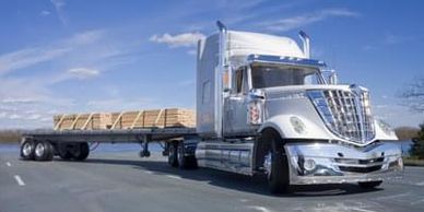 truck hauling a flat bed freight such as tanks, lumber, steel, logs and etc. 