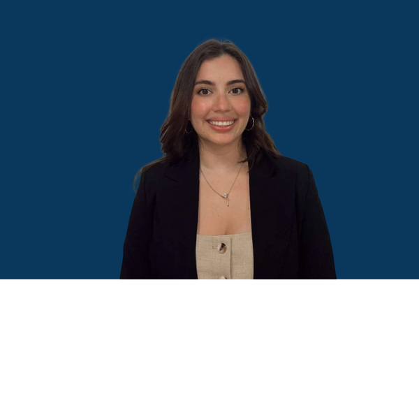 Smiling young woman in a black blazer against a blue background.