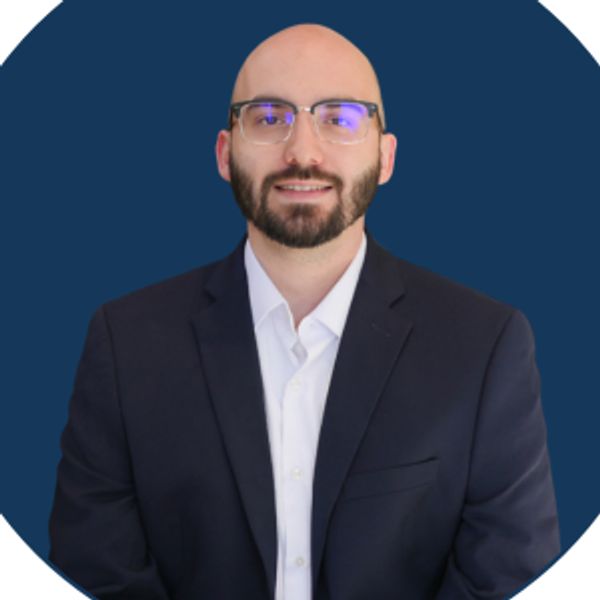 Portrait of a man with glasses and beard in a suit.