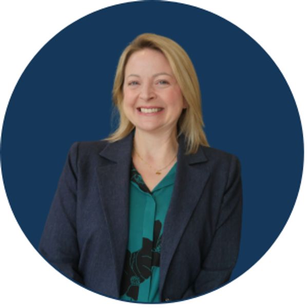 Smiling woman in blazer against dark blue background.