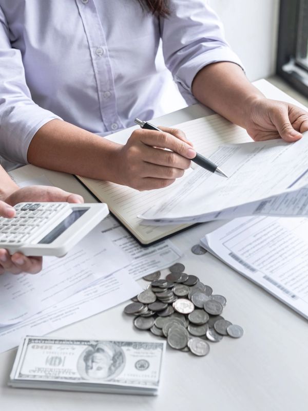 Person reviewing financial documents with money and calculator.