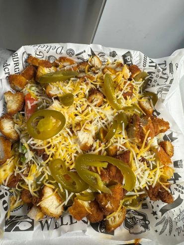 Plate of loaded fries with chicken, cheese, and jalapeños.
