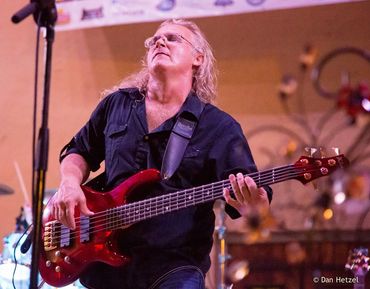 Musician passionately playing red electric bass guitar on stage.