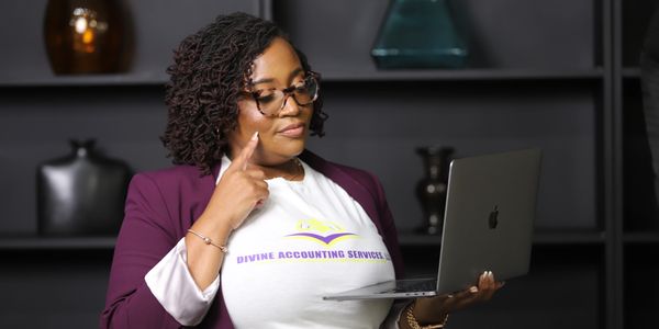 Woman working on a laptop, wearing a Divine Accounting Services shirt.