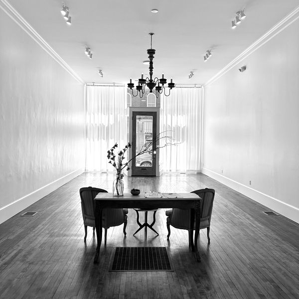 Event space with high ceilings, wood floors, elegant chairs, a chandelier, and light-filtering curta
