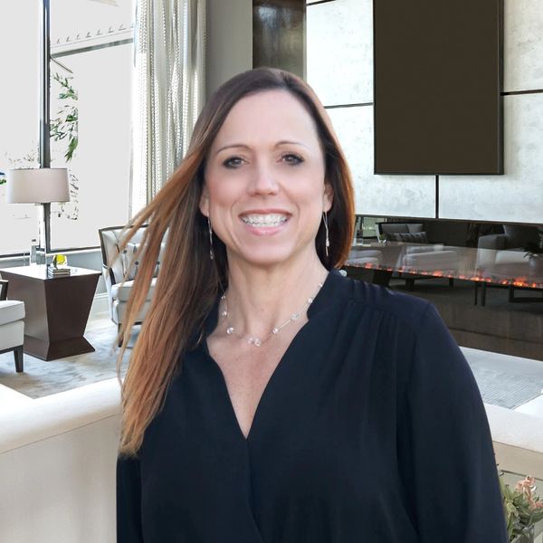 Smiling woman in black blouse standing in a modern living room.