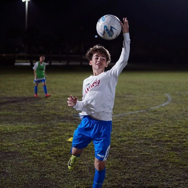 Boy playing soccer at night, preparing to throw the ball.