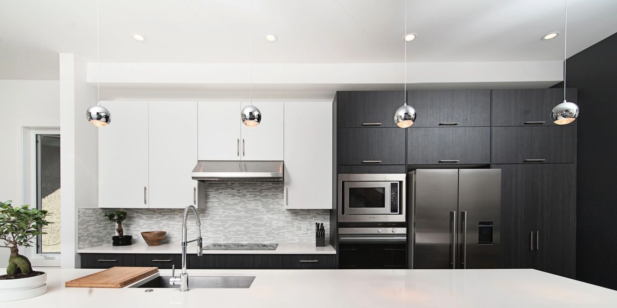 Modern kitchen with black and white cabinetry and stainless steel appliances.