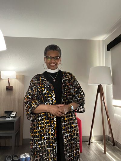 Woman standing indoors wearing glasses and a patterned kimono with a smile.