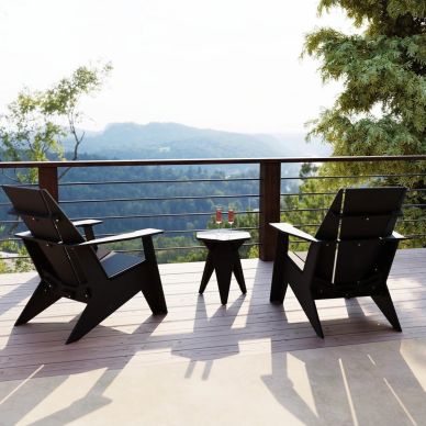 Two chairs and a table on a balcony with a mountain view.