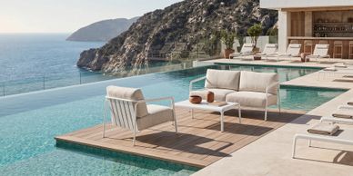 Modern poolside seating overlooking a scenic ocean and cliff view.