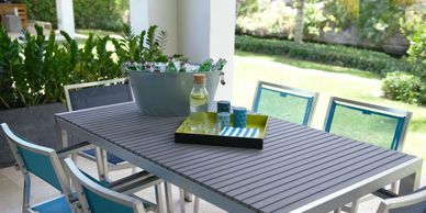 Outdoor patio table with chairs and a plant centerpiece under natural light.