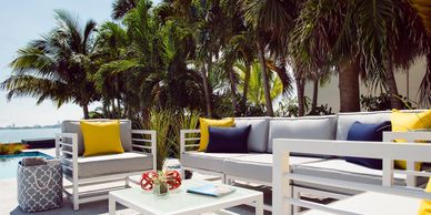 Outdoor patio furniture with colorful cushions set near palm trees.