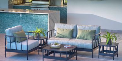 Modern outdoor patio set with cushioned seating and plants around.